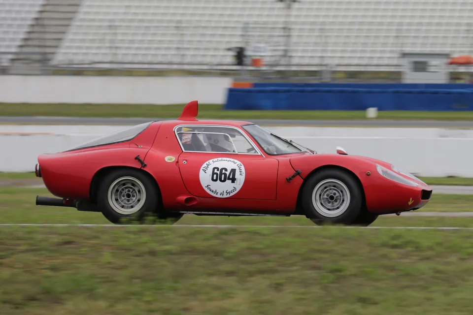 Red Abarth 1300 OT Periscopica racing at speed on a race track, side view