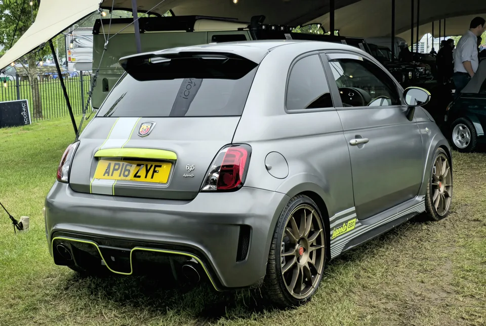 Matte grey Abarth 695 Biposto, rear three-quarter view, outdoor car show