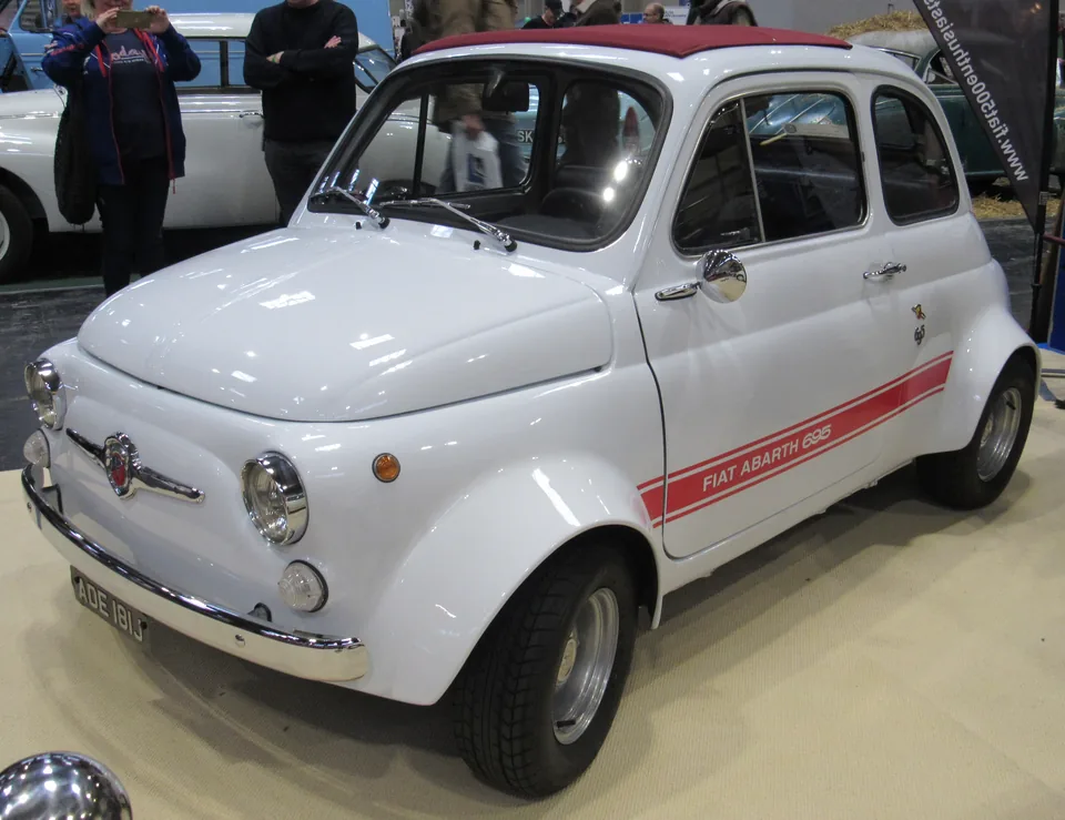 White Fiat-Abarth 695 SS with red side stripe, front three-quarter view, indoor car show