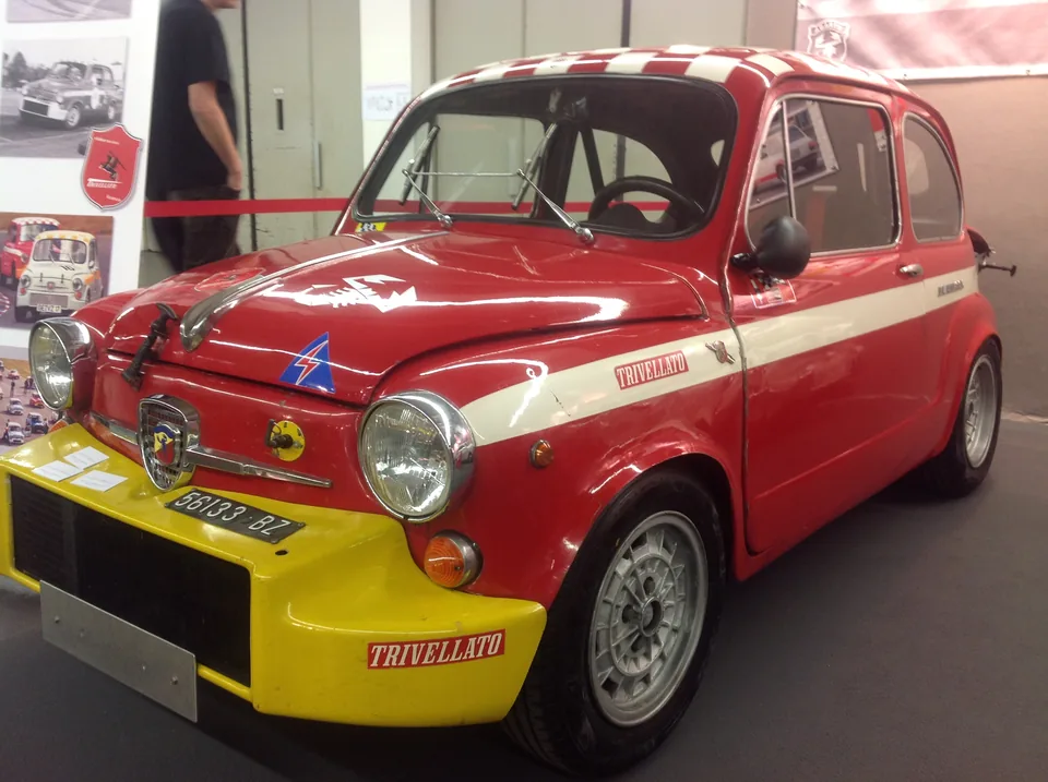 Red and white Fiat-Abarth 850 TC racing saloon, front three-quarter view, indoor car show
