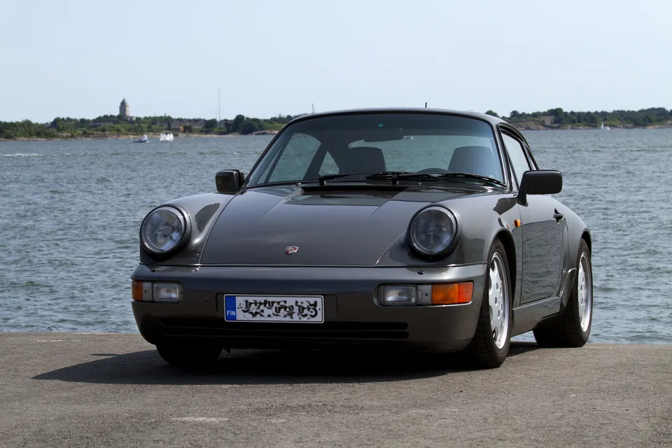 Slate grey Porsche 911 Carrera 4 (964) coupé on Design 90 wheels parked on a Helsinki waterfront, three-quarter front view