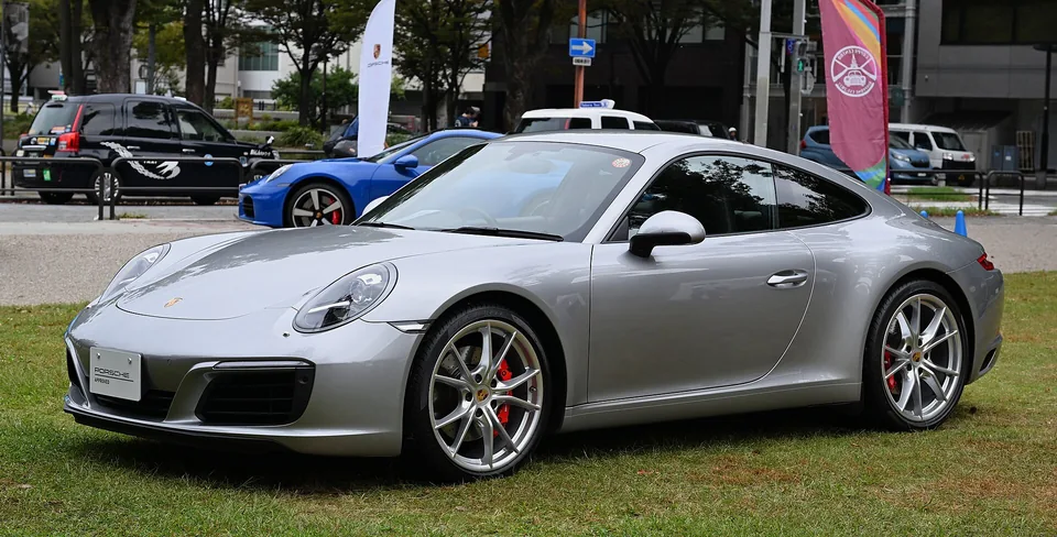 Silver Porsche 911 Carrera S (991.2) coupé on grass at a Japanese Porsche event, three-quarter front view