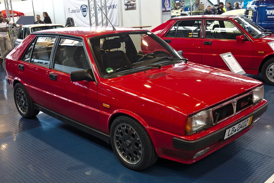 Red Lancia Delta HF Turbo, front three-quarter view at an indoor classic show