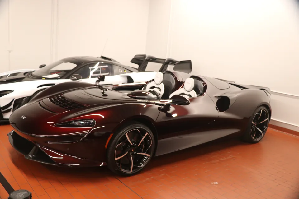 Dark red McLaren Elva with no windscreen, three-quarter front view