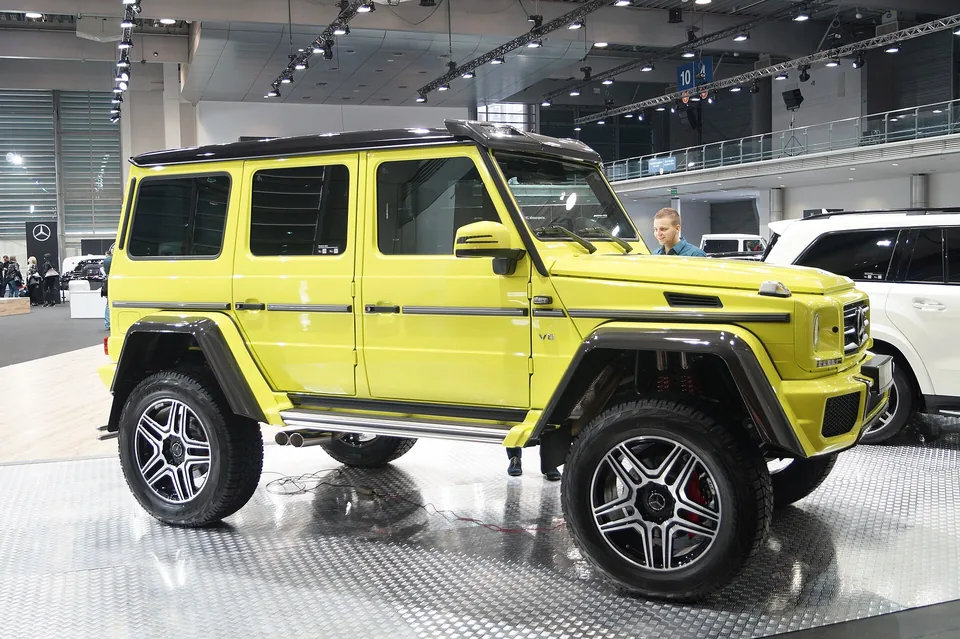 Yellow Mercedes-Benz G 500 4x4² at a motor show, side three-quarter view showing the portal axles