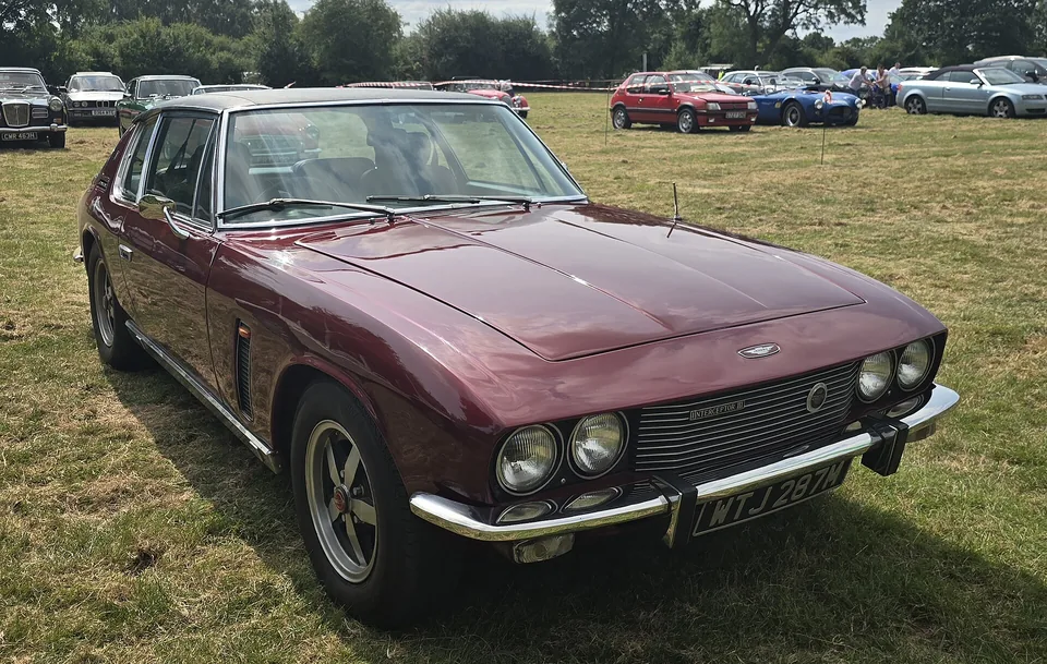 Maroon 1973 Jensen Interceptor III on grass at a classic show, three-quarter front view
