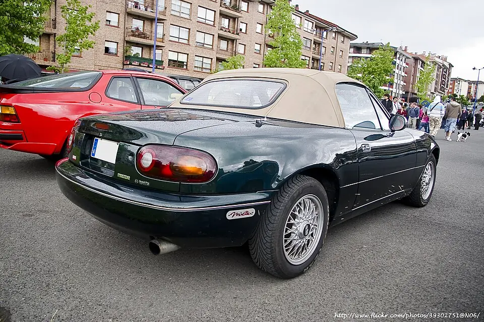 Red Mazda MX-5 Miata NA with pop-up headlights, three-quarter front view