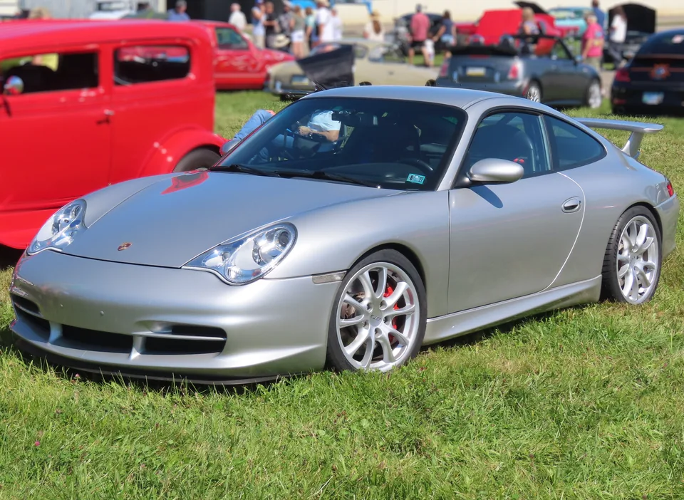 Arctic Silver 2004 Porsche 911 GT3 (996.2) with Turbo-style headlights and GT3 wheels on grass at a Pennsylvania car show, three-quarter front view