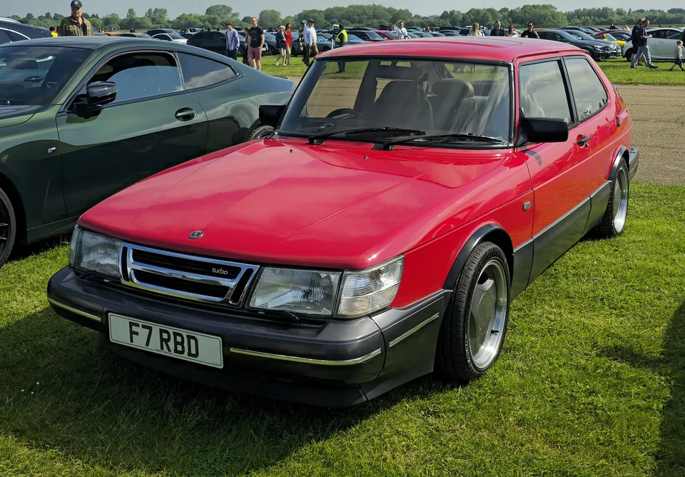Red Saab 900 Turbo 16 three-door hatchback at a classic meeting, three-quarter front view