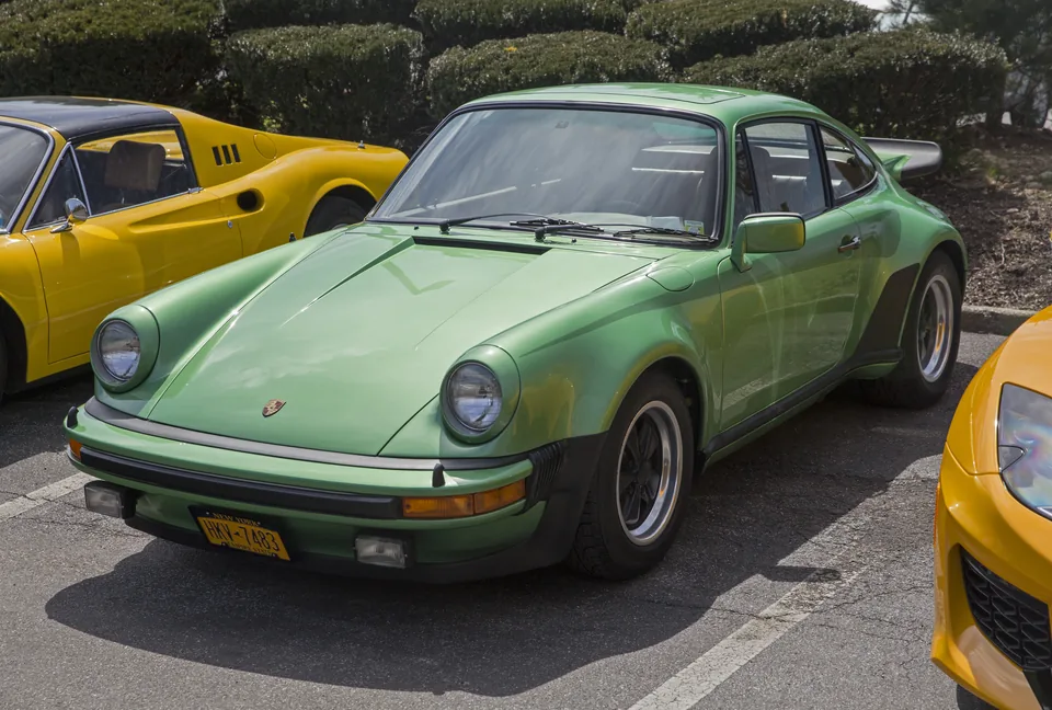 Emerald Green Metallic 1976 Porsche 930 Turbo 3.0 with flat whale-tail spoiler and Fuchs wheels in a New York car park, three-quarter front view