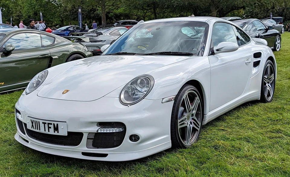 White Porsche 911 Turbo (997.1) coupé on grass at Salon Privé, three-quarter front view