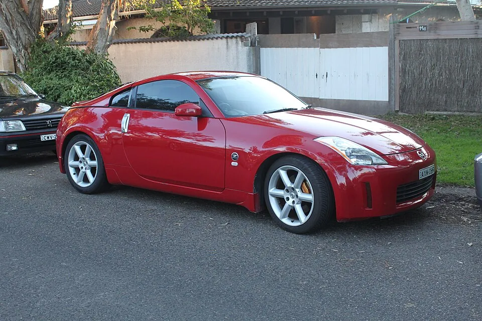 Red Nissan 350Z (Z33) Track coupe, front three-quarter view on a street